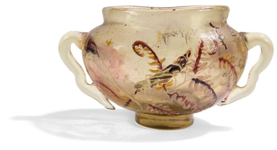 Émile GALLÉ (1846-1904)


Sauterelle, étoiles, fougères et fleurs champêtres
Coupe oblongue mouvementée sur talon à deux anses modelées et appliquées à chaud.
Épreuve en verre fumé au décor tournant, en partie dégagé à l'acide, réalisé aux émaux polychromes et achevé à l'or.
Circa 1895/1900.
Signé E. GALLÉ Nancy et marqué Déposé, à l'émail rouge sous la base.
Hauteur: 9,5 cm
Longueur: 16 cm
Provenance:
Collection Mme K., Paris