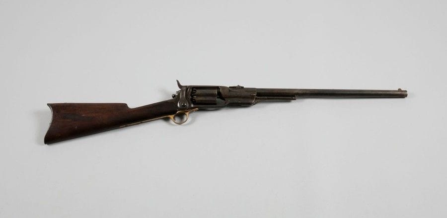 Rare carabine revolver Colt modèle 1855, cinq coups, calibre 56.
Canon rond à pans au tonnerre de 53 cm, hausse à feuillets à 600. Carcasse fermée, frappée sur le dessus «COL COLT HARTFORD C.T. U.S.A.», avec anneau de selle. Barillon à poinçons britanniques, marqué «PATENTED SEPT 10th 1850.» Pontet en laiton, numéroté «10070», plaque de couche en fer. Crosse en noyer américain.
B.E. Finition bronzée patinée.
