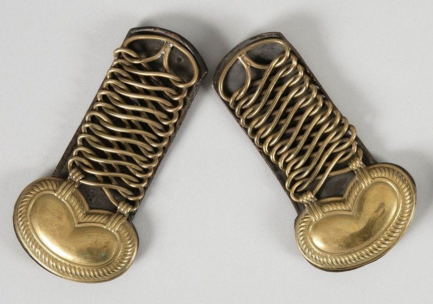 Paire d'épaulettes de chasseur d'Afrique.
En laiton, à anneaux en huit, finissant par un motif estampé.
Doublure en fort cuir brun avec marquage «01 22». Attache à crochet.
B.E. Époque Monarchie de Juillet (1832-1847).