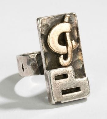 Jean DESPRES (1889-1980)

Rare bague moderniste en argent et or. La plateforme rectangulaire excentrée, à fond martelé, reçoit un décor de monogramme traité or et argent. Ce dessus repose sur un anneau présentant, également, une surface martelée.
Signé J. DESPRÉS, à la pointe à l’intérieur de l’anneau en grande partie effacé, et porte les poinçons de Maître Orfèvre et de garantie à l’extérieur. Poids: 16 g