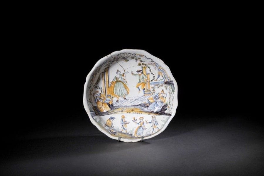NEVERS ou MOULINS
Grand saladier rond à bord contourné en faïence à décor polychrome d'un couple de danseurs sur une scène flanquée de colonne et surmontée de grappes de raisin, un joueur de violon sur la droite et deux couples assis de part et d'autre, dans la partie inférieure un homme jouant du hautbois, et une femme et deux hommes tenant des gobelets et casseroles.
XVIIIe siècle.
D.: 34,5 cm.
Accidents