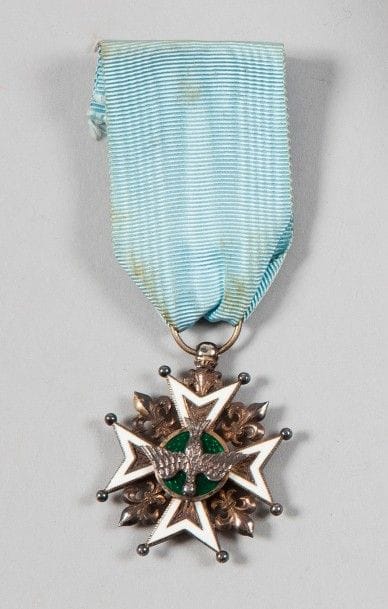 FRANCE 
Croix inspirée de l’ordre du Saint-Esprit. 
En vermeil, argent et émail. Ruban bleu ciel. Poinçon tête de sanglier. 
Ht : 4,5 cm - Poids brut : 22 g
SUP. Fin du XIXe siècle.