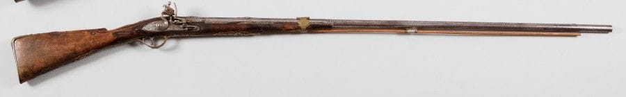 Fusil de chasse à silex.
Canon rond à pans, gravé et poinçonné au tonnerre. Platine et chien col de cygne gravés. Ressort à roulette. Garnitures en laiton ornées de masques en argent. Crosse en noyer.
E.M. Italie. Vers 1780. (Usure, accident au fût).