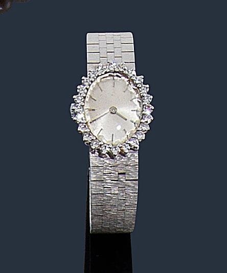 Montre de dame en or gris 18K (750‰), cadran ovale serti de diamants, fond satiné, index bâtons, bracelet ruban en or gris 18K, mouvement mécanique. 
Longueur : 17,7 cm environ. 
Poids brut : 44,3 g