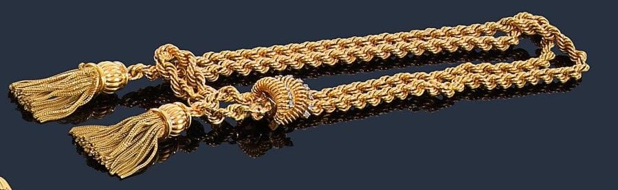 Collier en torsade d’or jaune 18K (750‰), le fermoir souligné de diamants, terminé de deux pompons godronnés retenant des floches. Poids brut : 86,9 g