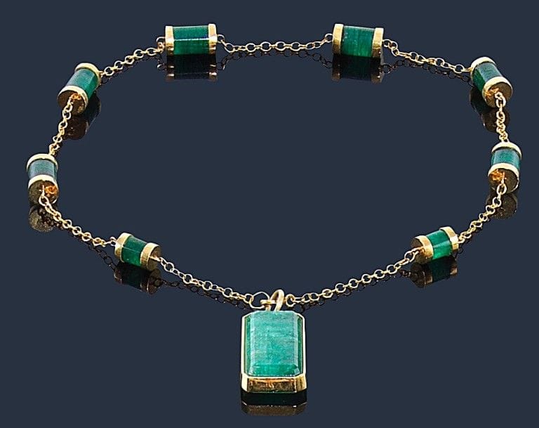 Collier en or jaune 18K (750‰), orné d’émeraudes tubulaires, retenant un pendentif en or 18K serti d’une émeraude de forme rectangulaire. 
Poids brut : 27,8 g 
(givres affleurants)