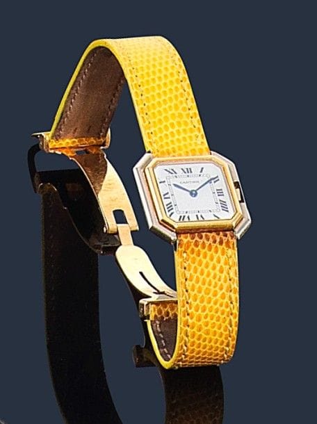 CARTIER.
Montre de dame en or 18K (750‰) et acier, modèle Ceinture, fond blanc, index chiffres romains, remontoir hexagonal, mouvement quartz, bracelet en lézard jaune à boucle déployante en or 18K, Signée et numérotée 782100204. Dans son écrin. Longueur : 17,5 cm environ. 
Poids brut : 31 g 
(mouvement à réviser)