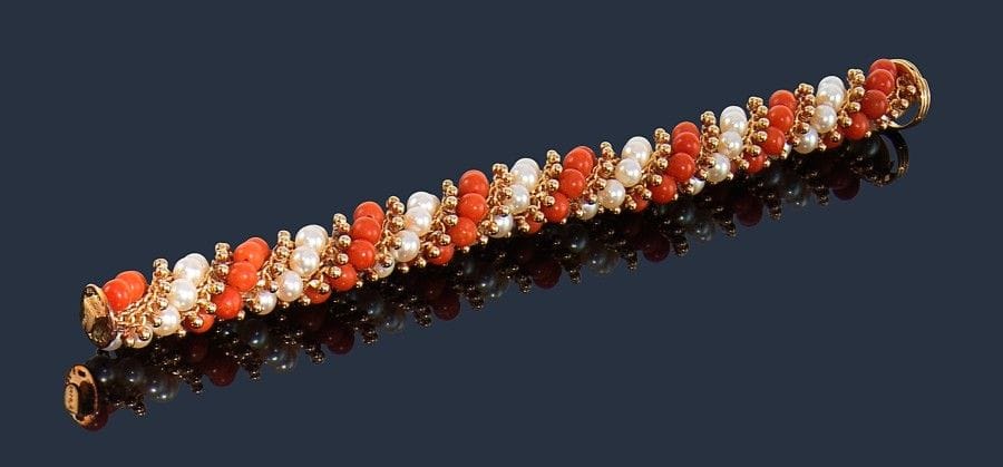 Van CLEEF & ARPELS.
Bracelet torsadé en or jaune 18K (750‰), billes de corail et perles de culture, modèle Twist. 
Signé et numéroté B. 8182. 
Longueur : 20,5 cm environ. 
Poids brut : 64,3 g
