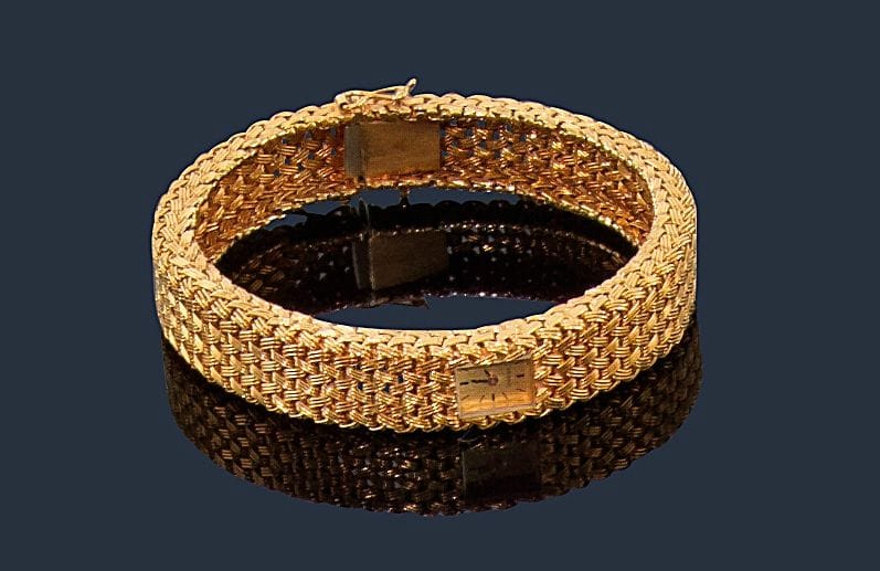 OMEGA.
Montre-bracelet de dame en or jaune 18K (750‰), cadran rectangulaire inscrit, fond satiné, index bâtons, bracelet en or tressé, mouvement mécanique. Dans son écrin. Longueur : 18,8 cm environ. 
Poids brut : 57,5 g