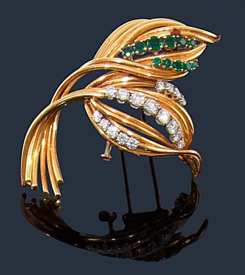 MELLERIO. 
Broche feuilles stylisées en fils d’or jaune 18K (750‰), agrémentée d’émeraudes et de diamants sur platine. Signée. 
Hauteur : 6 cm environ. Poids brut : 26,2 g