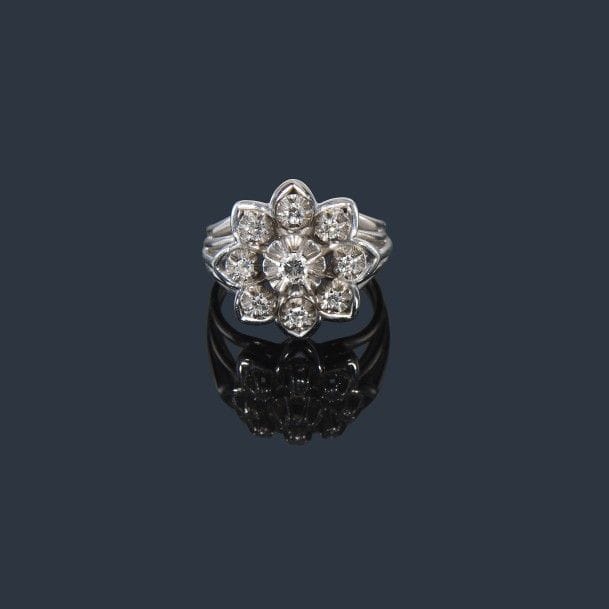 Bague en fils de platine et d’or gris 18K (750‰), en forme de fleur stylisée, sertie de 9 diamants, celui du centre plus important. Travail français des années 1960. 
Tour de doigt : 57. Poids brut : 8,8 g