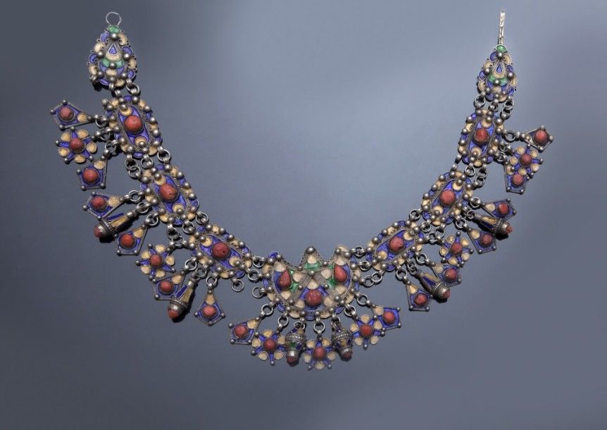 Collier, tazlagt, en argent, Algérie, Grande Kabylie, Beni Yenni, début XXe siècle
Neuf plaques en argent émaillé en polychromie jaune bleu et vert, à pendeloques diverses en étoiles, tonnelet, gouttes et cabochons de corail. Attache par un crochet.
Long. avec crochet : 47 cm
PB. : 215 g.
État : certains petits maillons reliant les plaques manquent.
An enameled silver necklace, tazlagt, with pendants, Algeria, Great Kabylia, Beni Yenni, 20th century