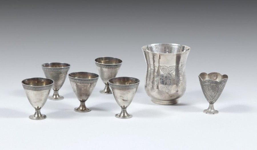 Six porte-tasses à café, zarf, et gobelet en argent, Turquie ottomane,
fin du XIXe siècle
Panse conique et piédouche à décor gravé d’une frise de tige végétale pour les cinq premiers, tughra illisible. Le dernier à bord lobé et à décor ciselé de tiges d’œillets et de roses dans un fleuron, et tughra d’Abdulhamid II (1876-1909),- joint un gobelet à panse cintrée à décor ciselé de rinceaux végétaux, tughra illisible. Poinçons sah et marques chechme sur chaque. 
H.: 6 cm (pour les six) ; 9,5 cm
PB : 279 g. 
Six silver cup holders, zarf, and a beaker, Ottoman, Turkey, late 19th century