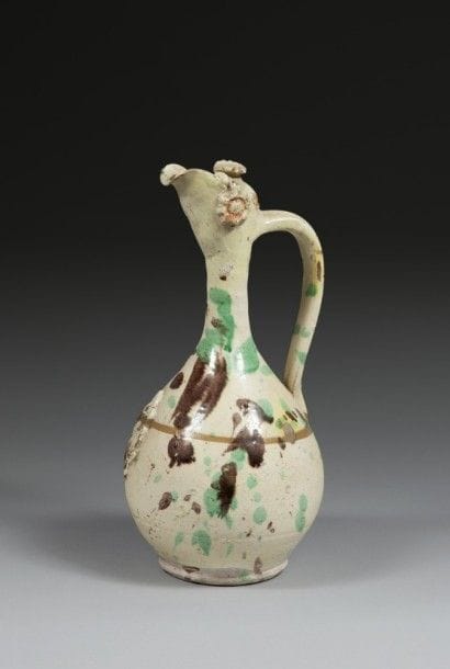 Aiguière à tête d’oiseau, Canakkale, Turquie, XIXe siècle
Panse piriforme en céramique argileuse rouge à décor de taches de glaçure vert et brun sur fond beige à rosettes et palmettes appliquées.
H. : 33 cm
État : quelques éclats sur la surface.
Cannakale ceramic jug, Turkey, 19th century