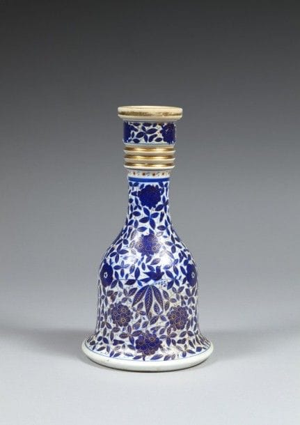 Base de huqqa, en porcelaine, Europe centrale pour l’Iran, fin XIX- début XXe siècle
En porcelaine à décor de fleurs et feuillage bleu et or. 
Dim. : 26 cm
État : décor effacé par endroits 
A porcelain huqqa base, Iran, late 19th- early 20th century
