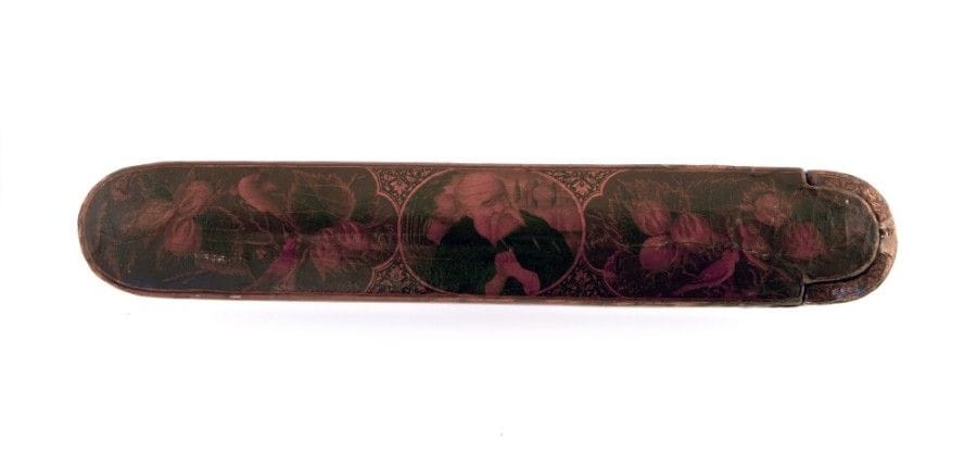 Plumier au saint homme, Iran qâjar, XIXe siècle
Plumier oblong en bois à décor peint en polychromie à rehauts d’or et laqué. Sur le couvercle, médaillon central au personnage aux mains jointes sur un fond d’édifices à croix, entouré de polylobes ornés de « gol o bolbol ». A la base, rinceaux floraux dorés sur fond rouge. 
Dim. : 23 cm 
État : éclats et restaurations
A polychrome lacquer wooden pencil case, Qajar Iran, 19th century