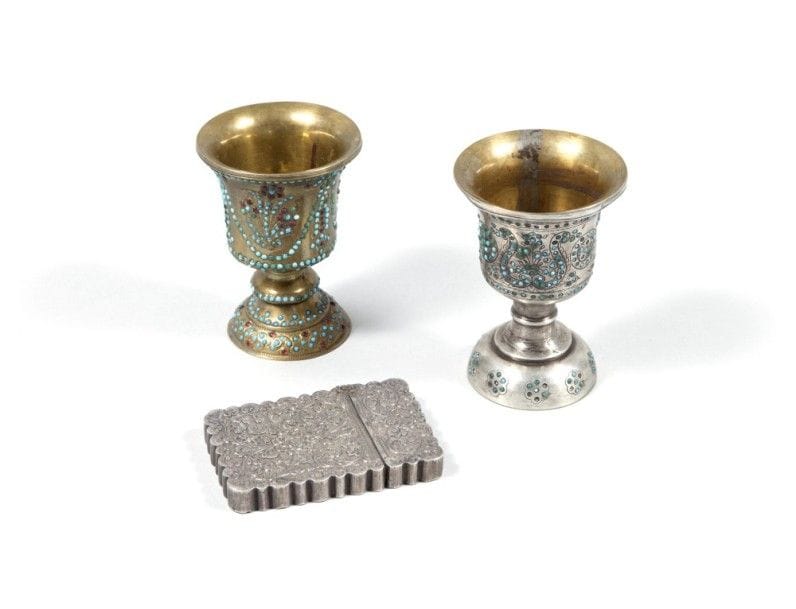 Deux fourneaux de narghilé et porte-cartes, Iran, XXe siècle
Deux fourneaux en laiton remontés sur piédouche à décor incrusté de perles couleur turquoise et grenat ou vert. Décor de guirlandes entourant des bouquets ou palmettes et rondeaux. Porte-cartes en argent polylobé à décor ciselé de rinceaux végétaux fleuris. 
Dim. : 9,1 x 6,5 cm ; 9,6 x 6,8 cm ; 8,5 x 6 cm
P. : 88 g.
État : manques de certaines perles.
Two nargileh bowls, Iran, 20th century