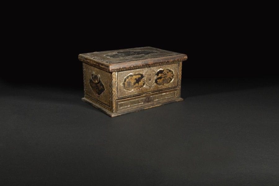 Coffre muni d’un tiroir à la partie inférieur en laque Namban avec galuchat et incrustations de nacre. Décor de cartouches mouvementés avec laque hiramaki-e or sur fond noir représentant des arbres et des fleurs, sur le couvercle d’un bouquet fleuri cerclé de nacre, sur le devant et les côtés de compositions florales, intérieur du couvercle orné d’une touffe de roseaux ; poignées latérales et entrée de serrure découpée en laiton..
Japon, époque Momoyama, fin du XVIIe siècle.
Longueur : 50,5 cm - hauteur : 28,5 cm - Profondeur : 35 cm.
(nombreux accidents et manques, restauration à la serrure du tiroirs).
