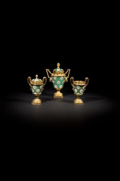 Garniture de trois vases pot-pourri en porcelaine de Sèvres à décor de cartouches de fleurs sur fond vert, la monture de bronze doré ajourée dans le haut à décor de cordelettes ; les anses brettées soutenues par un mufle de lion, reposant sur un piédouche feuillagé à guirlandes de feuilles de laurier ; (manque un couvercle)..
Époque Louis XVI (manque)..
H : 30 cm et 22 cm, L : 20,5 cm et 13,5 cm.
.
Provenance .
- Ancienne collection Arthur Gilbert, Christie’s New York, le 21 octobre 2005, lot 331..
- Sotheby’s New York, le 23 octobre 2013, lot 166..
Ce type de garniture mariant la porcelaine de Sèvres à une monture très tôt dans la période néoclassique a été décliné de différentes manières, la porcelaine bleu ou vert, avec ou sans cartouches de fleurs, en conservant le même modèle de monture. Madame Du Barry possédait une garniture de cinq vases à cartouches de fleurs sur fond vert livrée le 4 septembre 1770 par le célèbre marchand mercier Simon Philippe Poirier, réservée sous la Révolution par la Commission des arts « 2 vases en urne fond bleu de ciel à médaillons de fleurs et garnis de bronze doré ; 2 idem plus petits, 1 idem en forme d’œuf, estimé le tout 300 livres » (cité par C. Baulez, Le mobilier et les objets d’art de madame Du Barry , in « Madame Du Barry, de Versailles à Louveciennes », cat. exp., Paris, 1992, p. 77 note 80). Cette garniture est traditionnellement rapprochée de ce modèle dont on connaît par ailleurs un certain nombre d’exemplaires. Une garniture de trois vases à cartouches de fleurs sur fond vert illustrée dans S. Eriksen, Early neoclassicism in France, Londres, 1974, n°242) faisait jadis partie de la collection de madame Jules Fribourg, Eriksen mentionne également à cette occasion une autre garniture identique datée 1769 dans la vente d’Erich von Goldschmidt-Rothschild (Berlin, le 23 mars 1931, lot 206). Ces vases étaient vendus par la manufacture de Sèvres vers 1765-1770 sous le nom de « vases à monter 