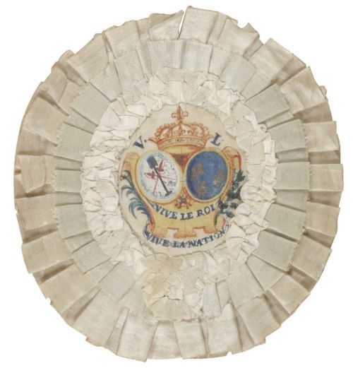 Rare cocarde de chapeau de la Fête de la Fédération en soie blanche au centre de laquelle sont peints une couronne Royale sous laquelle figurent à droite les armes de France et à gauche les attributs du Tiers Etat (bêche) et de la Noblesse (deux épées entrecroisées), soulignés par les mentions : Vive le Roi et Vive la Nation.
H de la cocarde : 12,2 cm, L : 11,1 cm
Dimensions du cadre postérieur : H : 24,9 cm, L : 20,8 cm
