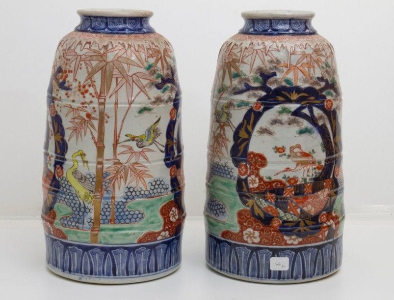 8029/1 JAPON, Imari - Époque MEIJI (1868 - 1912)
Paire de vases de forme cylindrique en porcelaine décorée en bleu sous couverte, rouge de fer et émaux polychromes de grues parmi les bambous et pins. 
(Restaurations). 
Hauteur : 39 cm
