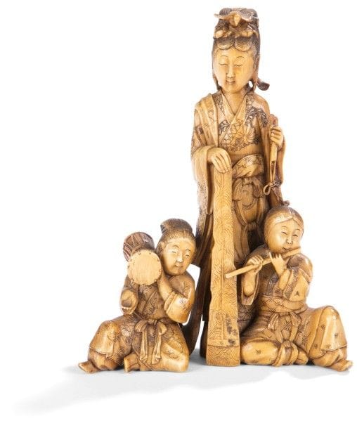 JAPON - Époque MEIJI (1868 - 1912)
Okimono en ivoire à patine jaune, Benten debout avec deux enfants jouant du tsutsumi et de la flûte. 
(Restaurations à l’éventail et petit accident au pan de sa robe). 
Hauteur : 12 cm