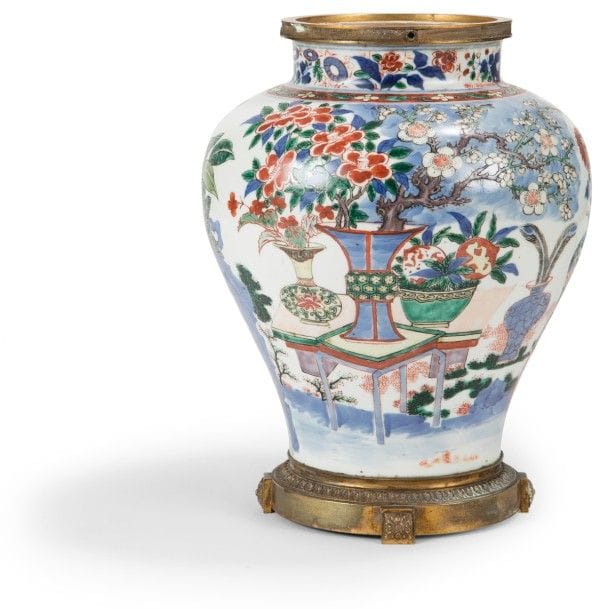 CHINE - Époque KANGXI (1662 - 1722)
Potiche balustre en porcelaine blanche décorée en bleu sous couverte de vases et jardinières fleuris, chrysanthèmes et pivoines. 
Montures en bronze doré. 
Hauteur : 31 cm