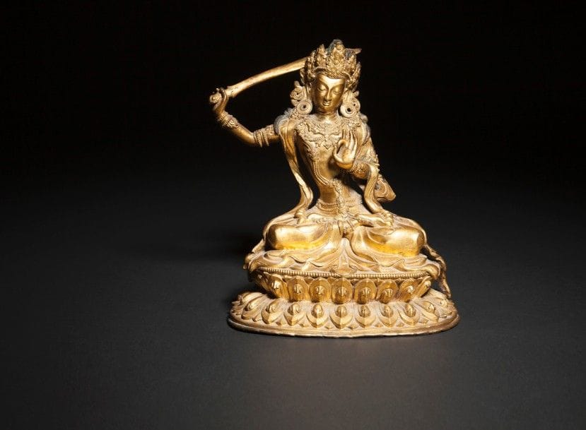 TRAVAIL SINO-TIBÉTAIN - XVIIIe siècle
Statuette de Manjusri en bronze doré, assis en padmasana sur un socle en forme de double lotus inversé, tenant dans sa main droite le khadga, la main gauche en vitarka mudra (geste de la loi ?). 
(Manque la tige de lotus). 
Hauteur : 19 cm
