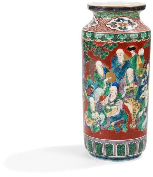 JAPON - Époque MEIJI (1868 - 1912)
Vase de forme cylindrique en porcelaine émaillée rouge à décor polychrome de rakan. 
Marque Kutani. 
Hauteur : 33,5 cm