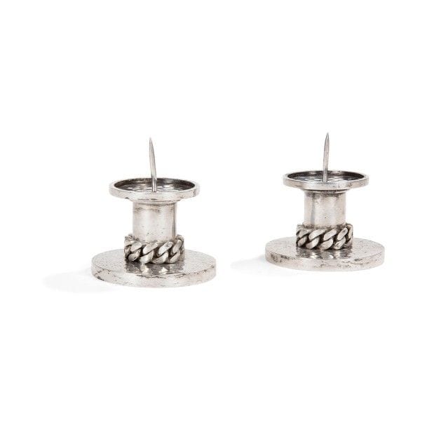 Jean DESPRÉS (1889-1980)
Paire de bougeoirs en métal argenté.
Les fûts cylindriques, traités lisses, reposent sur des bases circulaires à surface entièrement martelée et reçoivent des coupelles, également circulaires et martelées.
Une gourmette à maillons plats en application achève chacun des fûts.
Chaque pièce est signée J. DESPRÉS à la pointe au revers et porte à deux reprises le poinçon de Maître Orfèvre sur le pourtour de sa base.
Hauteur : 7,8 cm
