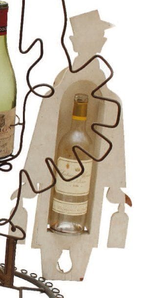 Charles LOUPOT (1892-1962)
Présentoir en bois peint (L. Latour ?), années 1950. 69,5 x 26 cm, prof. 5,6 cm, petits accidents. D'une poignée de magasins dont il hérite après la Grande Guerre, Étienne Nicolas construit en quelques années un véritable empire : parti de ses entrepôts modèles de Charenton, il règne en 1936 sur 304 dépôts. Son secret ? Une nouvelle approche de la vente (dont la mise en bouteille au château) et un usage massif de la publicité, domaine qu'il se réserve. Créé par Dransy en 1922, « Nectar » est décliné par les plus grands (Cassandre, Loupot, Lepape). Soucieux du moindre détail, il leur fait dessiner des présentoirs à bouteilles qui sont de véritables objets d'art. Ses tarifs de luxe participent de la même exigence. Aux trois premiers volumes d'Iribe (1930-1932) succèdent ceux de Cassandre puis, jusqu'au début des années 1970, il fait appel aux peintres de l'École de Paris. Référence : Alain Weill, Nectar comme Nicolas, Herscher, Paris, 1986.