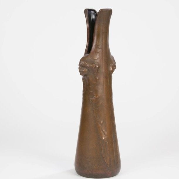 TRAVAIL 1900
Important vase fuselé au col fendu. Épreuve en galvanoplastie au décor de deux têtes d’enfants formant prises latérales. Intérieur émaillé bleu nuit. Numéroté 401 sous la base. H. : 55,5 cm 