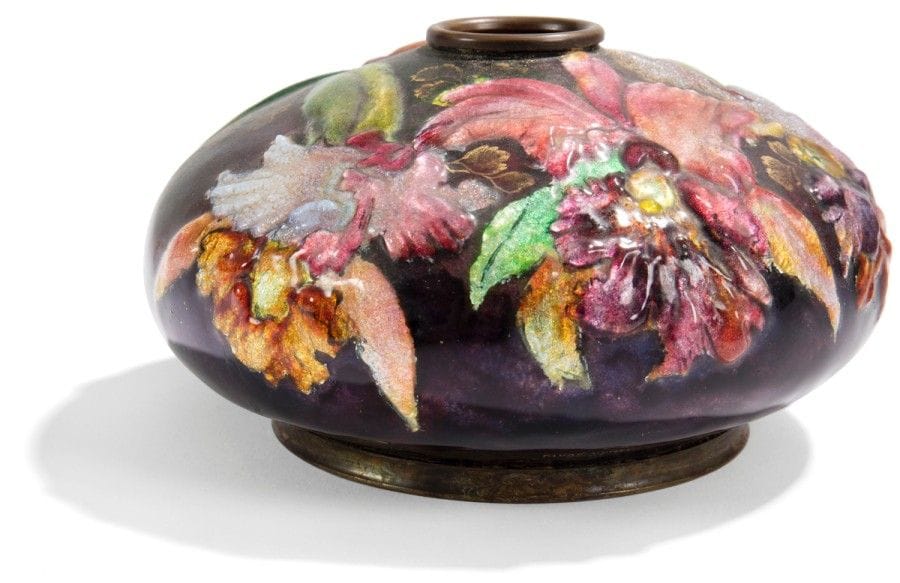 ÉMAUX D’ART Camille FAURÉ (1874-1956) à LIMOGES
Vase toupie, la panse très aplatie recevant un col annulaire. Épreuve en cuivre au décor tournant, d’iris bicolores et autres fleurs d’ornement, réalisé aux émaux polychromes et translucides sur fond d’un paillon coloré. Signé FAURÉ Limoges France près de la base et porte une étiquette Société pour l’expansion des industries d’art du Limousin sous la base. H. : 7,5 cm - D. : 14 cm