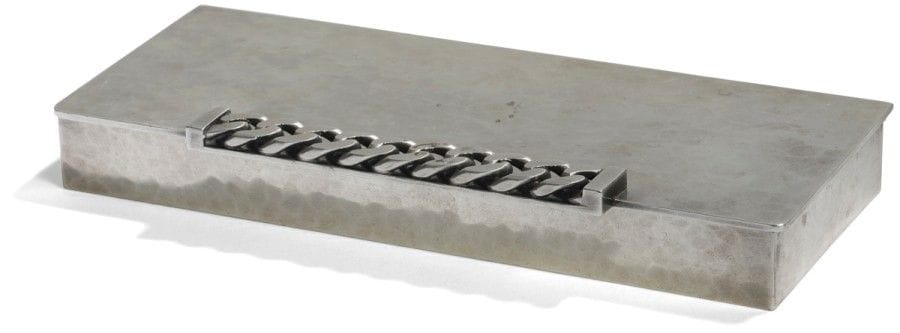 Jean DESPRÉS (1889-1980) 
Coffret à cigarettes en métal argenté à surface entièrement martelée. La prise formée d’une gourmette à maillons plats en large débordement. Signé J. DESPRÉS à la pointe sous la base. 2,8 x 20,3 x 9 cm