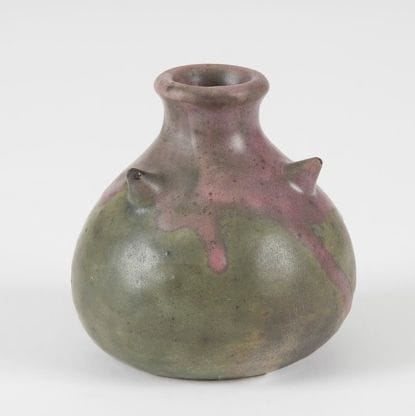 Théo PERROT (1856-1942)
Pot bursaire à col cintré. Épreuve en céramique émaillée vert à décor d’une coulure violette et de trois pointes sur l’épaulement. Usures aux pointes. Numéroté 313, VII et signé Théo PERROT sous la base. H. : 8,5 cm