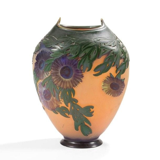 Établissements GALLÉ (1904-1936)
Ficoïdes marins dit aussi Griffes de sorcières
Rare et important vase ovoïde méplat reposant sur un talon débordant et au col étiré à la pince à chaque extrémité.
Épreuve en verre multicouche au décor double face très profondément dégagé à l'acide, les cœurs des fleurs traités bleu irisé, les pétales colorés violet, les tiges et les feuilles, dites Doigts de sorcières, apparaissant en très haut-relief et vert profond sur un fond jaune dense et opalescent nuancé de parme.
L'ensemble du décor est repris en gravure à froid.
Un léger éclat sous la base.
Signé GALLÉ, en réserve gravé en camée à l'acide.
Hauteur : 43 cm
Bibliographie :
Le verre en France, d'Émile Gallé à nos jours - Janine Bloch-Dermant, Les éditions de l'amateur, Paris, 1986.
Modèle identique reproduit page 35.