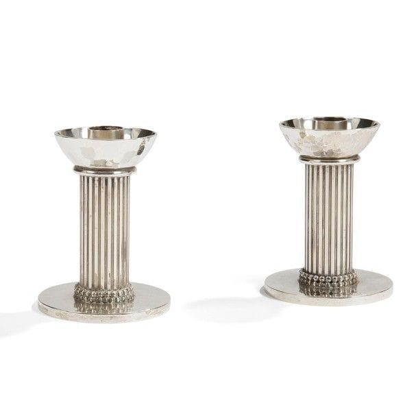 Jean DESPRÉS (1889-1980)
Paire de bougeoirs de table en métal argenté.
Les fûts cylindriques cannelés reposent sur d'épaisses bases circulaires, à surface martelée, ornées chacune d'un rang tournant de sphères.
Les parties hautes sont constituées des bobèches martelées reposant sur un anneau.
Chaque œuvre est signée J. DESPRÉS à la pointe au revers.
Hauteur : 10,6 cm
Provenance :
Ancienne Collection Mme G. (Nantes - France), œuvres acquises par ses beaux-parents (Isle-sur-Serein près d'Avallon) directement auprès de l'artiste.