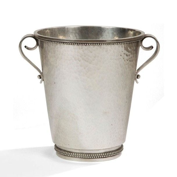 Jean DESPRÉS (1889-1980)
Seau à champagne moderniste en métal argenté.
Le corps à surface martelée reçoit deux prises en volutes, traitées lisses, et accueille une double rangée perlée sur le talon en retrait et une simple sous le pourtour débordant de la bordure.
Signé J. DESPRÉS à la pointe sous la base.
Hauteur : 23 cm
Provenance :
Ancienne Collection Mme G. (Nantes - France), œuvre acquise par ses beaux-parents (Isle-sur-Serein près d'Avallon) directement auprès de l'artiste.