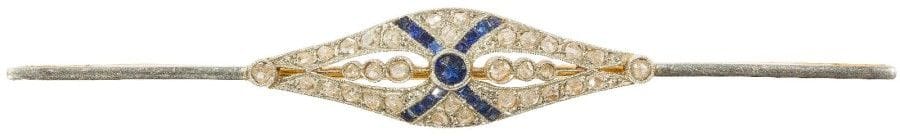Broche fuseau en or jaune 18K (750‰), ajourée au centre, sertie de pierres bleues et de diamants taillés en roses. 
Travail français des années 1910. 
Long. : 8 cm environ. 
Poids brut : 5,6 g