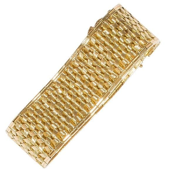 Bracelet ruban en or jaune 18K (750‰) tressé, en motifs vannerie imbriqués. 
Dimensions : 20 x 2,6 cm environ. 
Poids : 74,7 g (déformation)