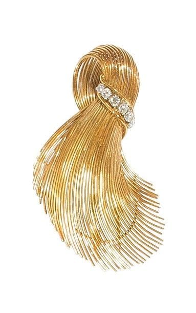 Broche-clip en fils d’or jaune 18K (750‰) formant une plume stylisée, agrémentée d’un lien serti de 6 diamants sur platine. 
Travail français des années 1960. 
Haut. : 6 cm environ. 
Poids brut : 15,7 g