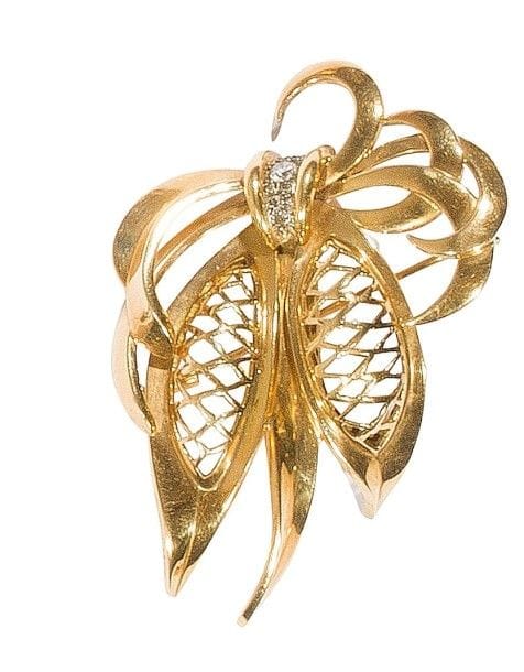 Broche en or 18K (750‰) ajouré formant des feuilles stylisées réunies par des petits diamants. 
Travail des années 1940. 
Haut. : 7 cm environ. 
Poids brut : 26,1 g