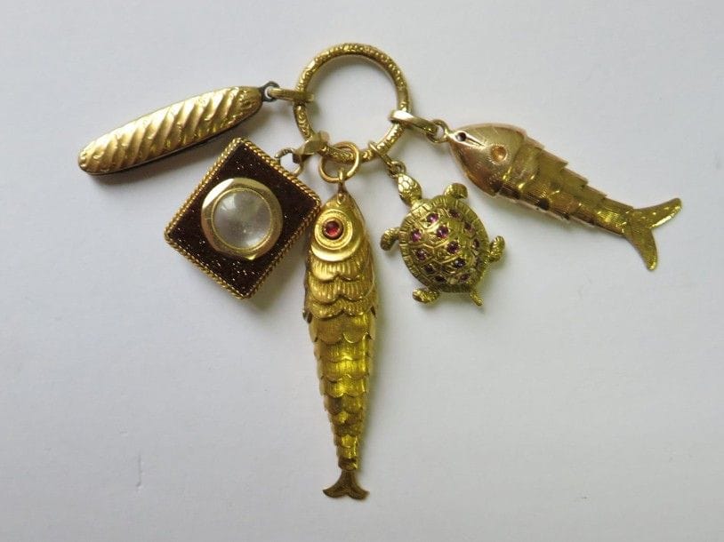 Anneau en or 18K (750‰) retenant en pampilles 5 breloques en or ou en métal : deux poissons, un canif (métal), une tortue et un porte-souvenir en aventurine. 
Poids brut : 14,8 g