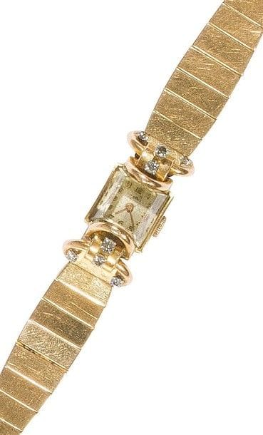 Montre de dame en or jaune 18K (750‰), cadran carré, les anses formant des arceaux agrémentés de petits diamants, bracelet articulé en or 18K. 
Travail français. 
Long. : 16,5 cm 
Poids brut : 66 g (mouvement à réviser)
