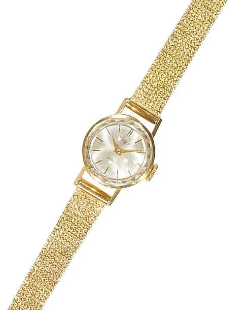 Montre de dame en or jaune 18K (750‰), cadran rond, fond satiné, index bâtons, bracelet ruban souple en or 18K, mouvement mécanique. 
Long. : 16 cm environ. 
Poids brut : 18,4 g (remontoir métal)