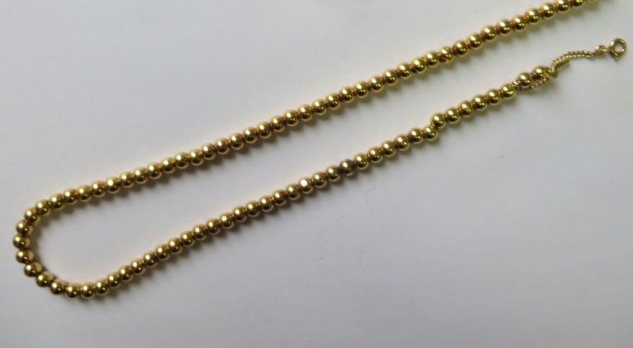 Collier en billes d’or jaune 18K (750‰) coulissant sur une chaîne d’or. 
Long. : 38 cm environ. 
Poids : 17 g (enfoncements)