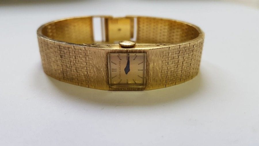 MAPPIN & WEBB. Montre de dame en or jaune, cadran carré, fond satiné, index bâtons, bracelet ruban plat en or satiné, mouvement mécanique. 
Poids brut : 54,3 g