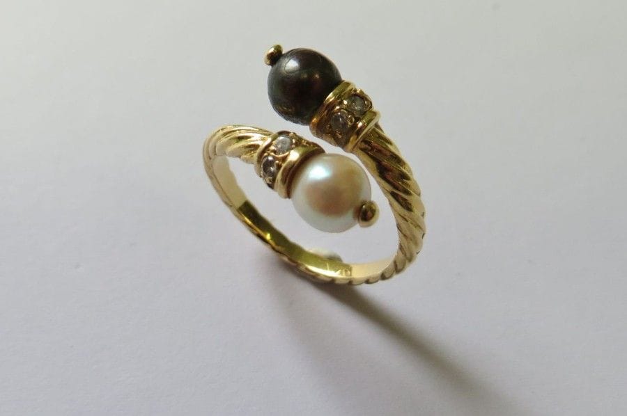 Bague toi et moi en or jaune 18K (750‰) torsadé, ornée d’une perle blanche et d’une perle noire de culture, agrémentée de petits diamants. 
Tour de doigt : 52. 
Poids brut : 4 g
