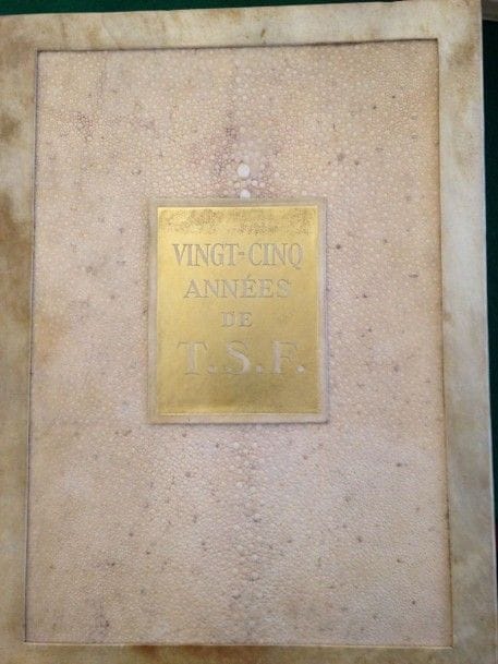 [TSF]. Vingt-cinq années de T.S.F. S.l. : Société française radio-électrique, [1934]. — In-4, parchemin ivoire encadrant sur les plats une grande pièce de galuchat ivoire, plaque dorée portant le titre au centre du premier plat, dos à faux nerfs orné de filets dorés, tête dorée, non rogné, étui (Jean Duval). 
Superbe ouvrage commémoratif, publié à l’occasion de 25e anniversaire de la création la Société Française Radio-électrique. Il comprend un beau portrait d’Émile Girardeau par IACOVLEFF, tiré en sépia, plusieurs centaines de graphiques, statistiques et photos ainsi que 3 étonnantes et belles planches en couleurs sur aluminium, dont une à double page.
Très bel exemplaire dans une reliure originale en galuchat de Jean Duval, spécialement imprimé pour monsieur Germain-Martin, ministre des finances et ancien ministre des P.T.T.
Quelques rares rousseurs, sans gravité.