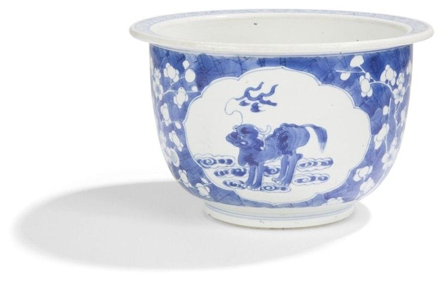 CHINE - Époque KANGXI   (1662 - 1722)
Jardinière en porcelaine décorée en bleu sous couverte de réserves polylobées ornées de sujets mobiliers sur fond de cerisiers en fleurs et miroir brisé. (Fond percé). Hauteur : 15,5 cm